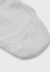 Calcetín deportivo blanco que presenta una puntera texturizada con un patrón de olas y una tela suave. El diseño asegura comodidad y un ajuste seguro.