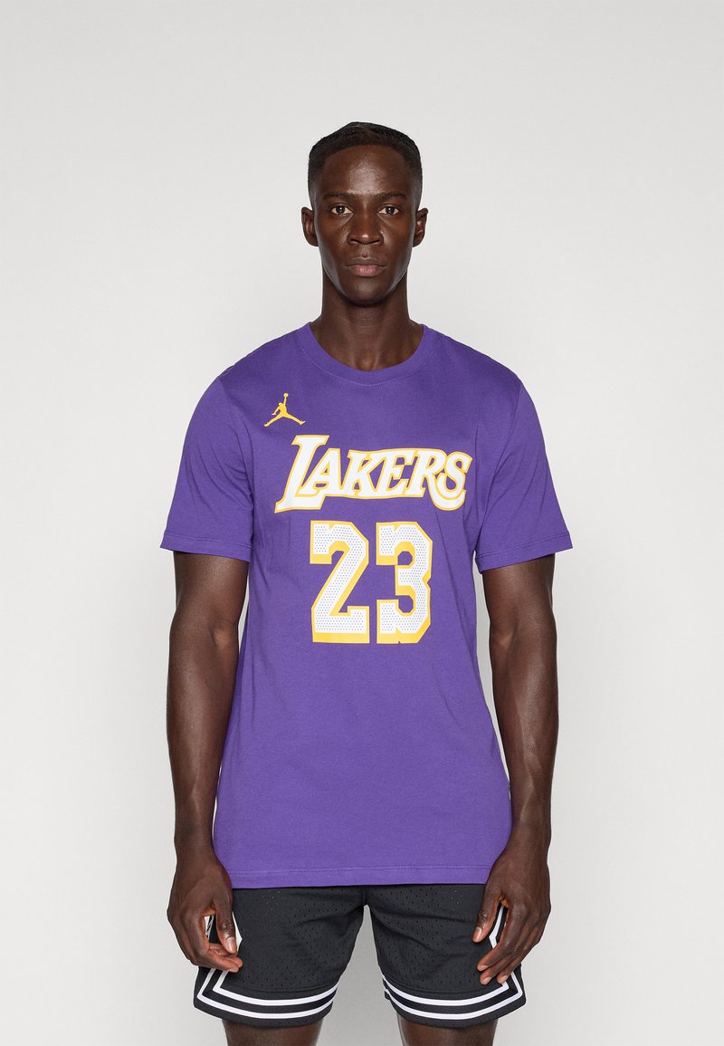 Ljubičasta majica s natpisom "Lakers" i brojem "23" u žutom printu, s malim žutim Jordan logotipom na lijevom ramenu.