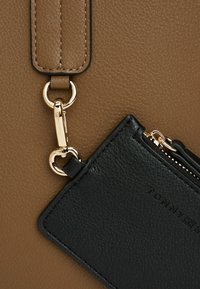 Bruine leren schoudertas met gouden hardware; bijgevoegd zwart leren kaarthouder met rits en geperst logo-detail.