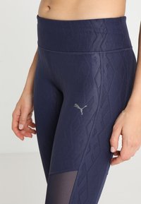 Marina byxor med en subtil diamantstruktur, hög midja och en PUMA-logga i silver. Har en meshdetalj på underbenet.