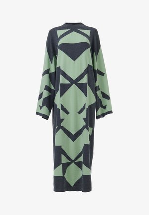 Robe longue avec un motif géométrique en vert foncé et noir, confectionnée dans un matériau tricoté doux avec des manches larges et un col rond.