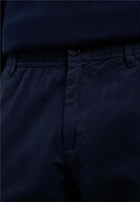 Pantalones de algodón azul marino con cintura elástica, cierre de botón y bolsillos laterales. Textura suave con costuras mínimas visibles.