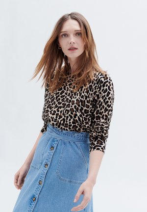 Leopardprint lange mouwen top gecombineerd met een hoog-waisted spijkerrok met een knopen voorkant en een brede tailleband.