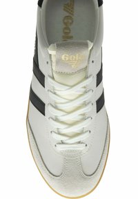 Witte sneaker met zwarte strepen, suède neuskap, vetersluiting en een gouden logo op de zachte nylon tong. Rubberen zool voor grip.