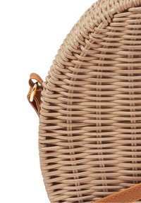 Round woven basket bag in beige with a textured pattern. Features a leather strap and gold hardware accents.