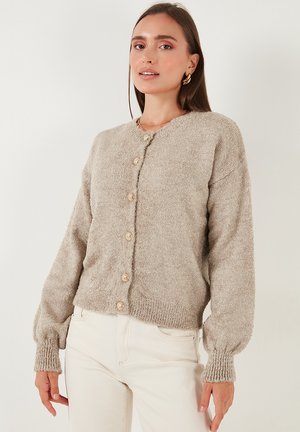 Beige knitted cardigan with a round neckline, button front, ribbed cuffs and hem, and a textured finish. Suitable for casual wear.