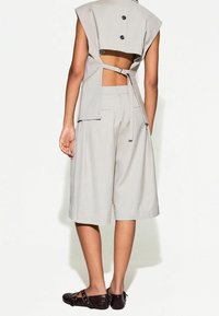 Ljusgrå tvådelad outfit med en kort topp med utskärning bak och vida shorts. Texturerat tyg och synliga framfickor.