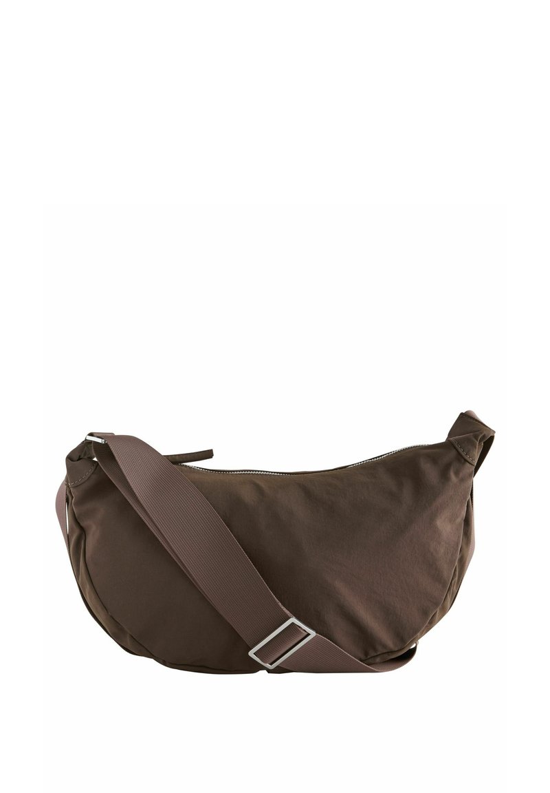 Brun stof sling taske med en buet form, lynlås lukning og justerbar rem. Har en glat overflade og minimalistisk design uden synlige detaljer.
