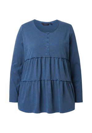 Sininen pitkähihainen paita, joka on valmistettu pehmeästä kankaasta. Siinä on pyöreä kaula-aukko, nappilista sekä kerroksellinen muotoilu, jossa on frilla-tyylisiä yksityiskohtia.