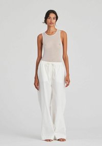Beige sleeveless top with a round neckline paired with white wide-leg pants featuring an elastic waistband and drawstring detail.