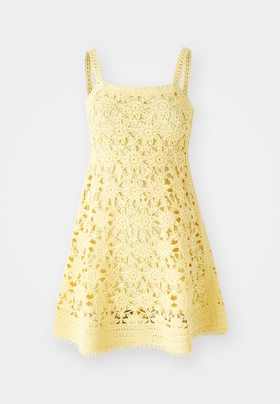 Dzeltena tamborēta kleita ar kvadrātveida dekoltē, plānām siksnām un ziedu rakstu. Tam ir izplestais siluets ar viļņotu apakšmalu.