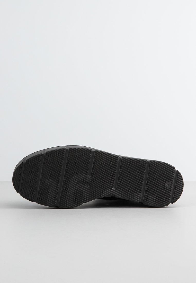 Schwarze Sneaker-Sohle mit einer strukturierten GummOberfläche, die mehrere Rillen und Abschnitte für besseren Halt aufweist. Sauberes, minimalistisches Design.