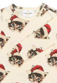 Tejido de crema con textura acanalada que presenta impresiones repetidas de gatitos con sombreros rojos de Santa, con ojos azules y un detallado acabado en el pelaje. Cierre a presión en el hombro.