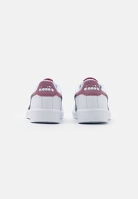 Vita sneakers med rosa och grå accenter. Slät syntetisk material, vadderad hälla, texturerad gummisula och logotyp på baksidan.