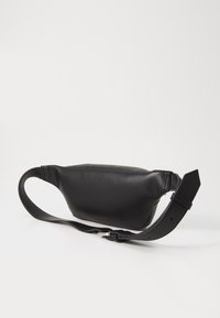 Sorte læder bæltetaske med en glat tekstur, buet form og justerbar rem. Har lynlåslukning og minimalistisk design.