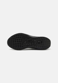 Semelle extérieure de chaussure de sport noire présentant un motif texturé avec des formes hexagonales et en forme de diamant pour une meilleure adhérence et traction.