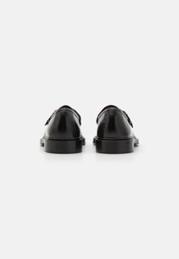 Mustad mustad nahast kingad siledast viimistlusest, ümarate varvaste, madalate kontsade ja minimalistikku disainiga. Ülalt kaunistamiseks on kaks dekoratiivset rihma.