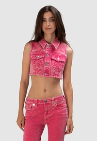 Skrócony różowy dżinsowy kamizelka z kołnierzykiem, srebrnymi guzikami i dwiema przednimi kieszeniami. Zniszczona tekstura z postrzępionym dołem.