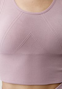 Svetlofialová športová podprsenka s hladkým povrchom, s jemnými geometrickými vzormi a rebrovaným spodným pásom pre väčšiu podporu.