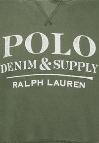 Felpa verde oliva con testo bianco. Presenta in evidenza le parole "POLO DENIM & SUPPLY" e "RALPH LAUREN". Texture morbida.
