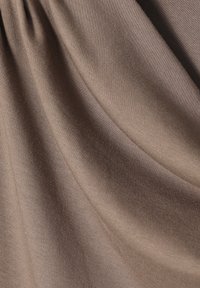 Hnědá látka s hladkou texturou, s jemným horizontálním žebrováním. Materiál se jemně splňuje, což ukazuje jeho pružnost.