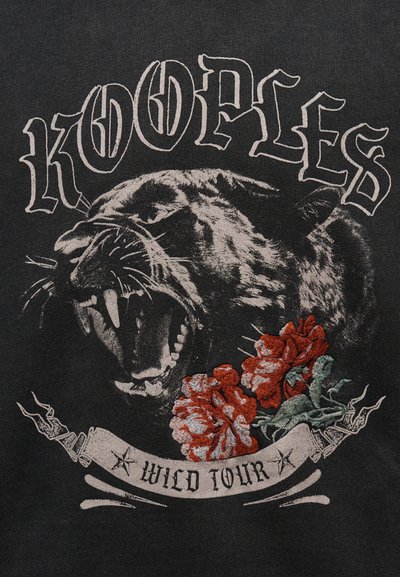 Κεφάλι πάνθηρα που βρυχάται με ανοιχτό στόμα πάνω από κόκκινα και πράσινα κεντητά λουλούδια, γοτθικό κείμενο "KOOPLES" και πανό με την επιγραφή "WILD TOUR" σε μαύρο φόντο.