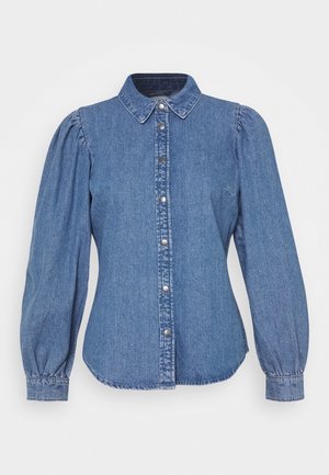 Chemise en denim bleu à manches longues avec épaules bouffantes, col pointu et fermeture par boutons-pression sur le devant.