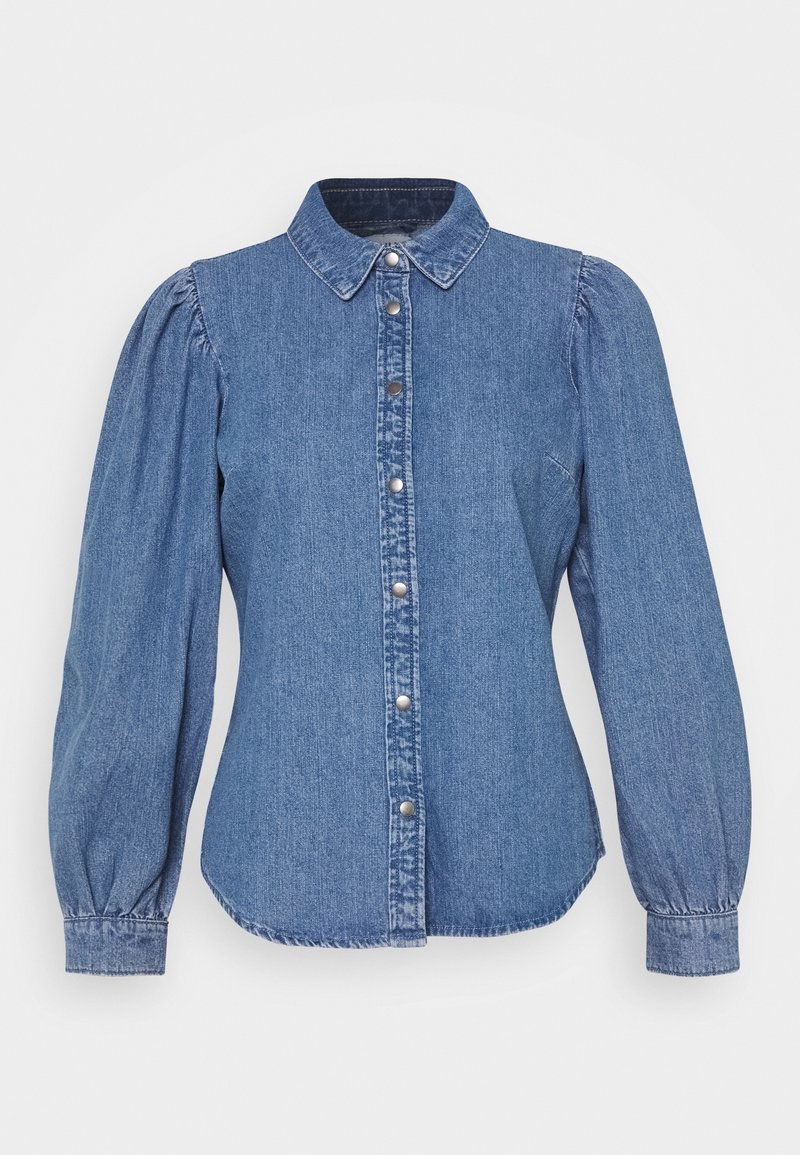Chemise en denim bleu à manches longues avec épaules bouffantes, col pointu et fermeture par boutons-pression sur le devant.