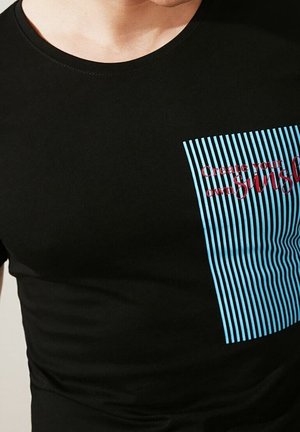 Sort t-shirt med lodret stribet lomme i blå og teksten "Create your own sunshine" i rødt.