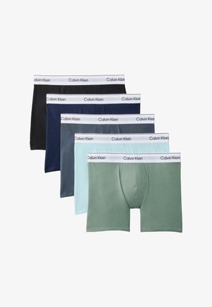Cinco pares de bóxers para hombre en negro, azul marino, gris, azul claro y verde con cinturillas blancas de Calvin Klein, dispuestos en una pila en forma de abanico.