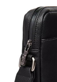 Borsa in pelle nera con finitura strutturata, dotata di cerniera argentata e dettagli in metallo. Vista angolata che evidenzia le cuciture e la tracolla.