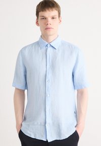 Light blue short-sleeve shirt with a button-down collar, made of textured fabric, featuring a straight hem and white buttons.