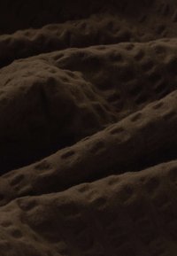 Tissu brun foncé à texture gaufrée avec des plis doux et un motif en grille légèrement en relief.