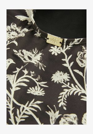 Black fabric with white floral pattern featuring leaves and flowers. Satin texture and rectangular gold-tone tag with floral engraving.