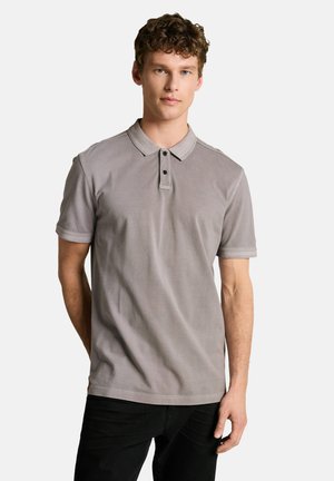 Man wearing a gray short-sleeve polo shirt with two buttons, standing against a plain white background.