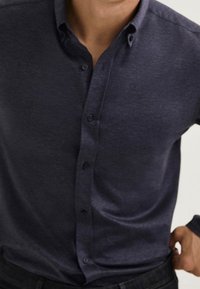 Camicia azzurra scuro con bottoni realizzata in tessuto testurizzato. Presenta un colletto classico e bottoni frontali. Vestibilità slim con una finitura liscia.