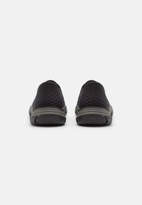 Souliers noirs à enfiler avec dessus texturé, bout rond et semelle gris clair. Le design inclut un motif en diamant et un accent de talon rembourré.