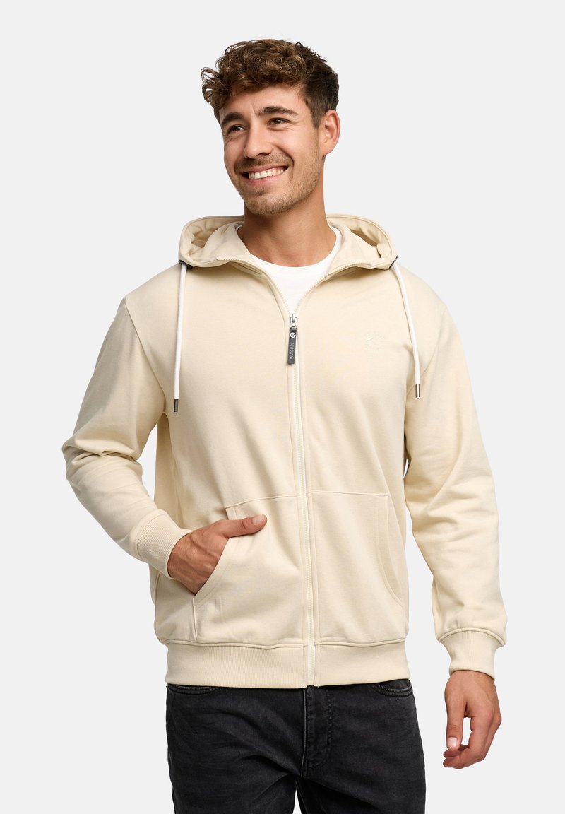 Lichtbeige zip-up hoodie met capuchon, trekkoorden, voorzakken en geribbelde boorden. Glad stoftextuur en minimale merkaanduiding.