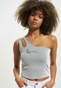 Top în dungi, scurt, cu un umăr, de culoare albă și neagră, cu textură ribbed și un design brodat în față.