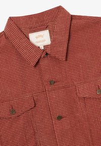 Červená kockovaná košeľa na gombíky s vreckami na hrudi a kovovými gombíkmi, veľkosť XL, s golierom a viditeľnou značkovou etikettou.