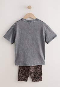 Szürke pamut rövid ujjú póló barna leopárdmintás rövidnadrággal. Mindkét ruhadarab puha anyagból készült és kényelmes szabású.