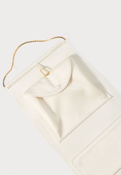 Krémově zbarvená taštička s klopou, zlacený řetízkový popruh a hladký textilní povrch. Zobrazeny jsou dvě oddělené kapsy.