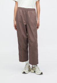 Καφέ, φαρδιά παντελόνια με ελαστική μέση και πλευρικά κουμπιά με τρουκ, κατασκευασμένα από ελαφρύ ύφασμα.