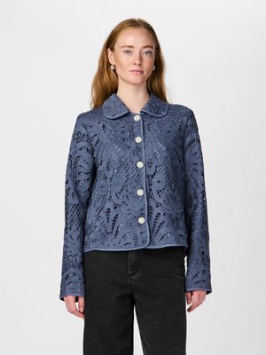 Blondejakke i dyp blå med krage, lange ermer og utsmykkede blomsterskjæringer med perleknapper til lukking.