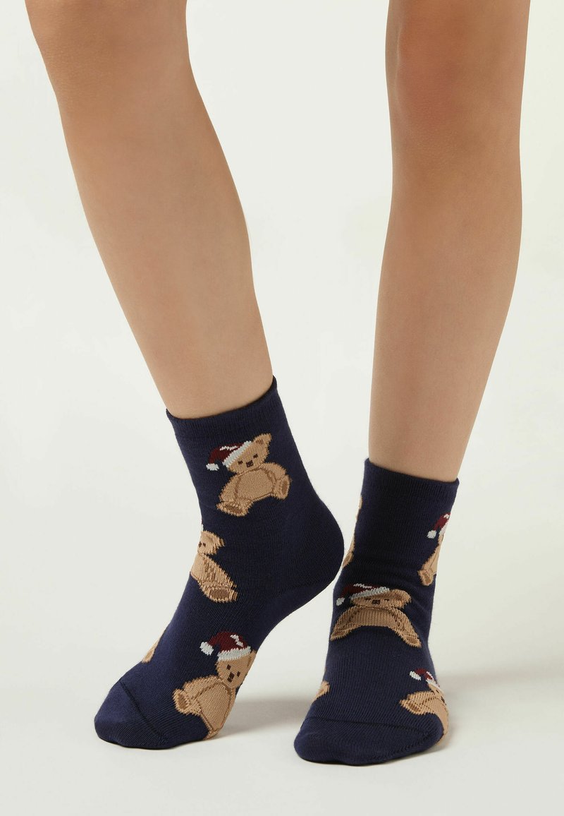 Marine ankelsokker lavet af bomuldsblanding med strikkede teddy-bear mønstre iført røde og hvide hatte, med en glat tekstur.