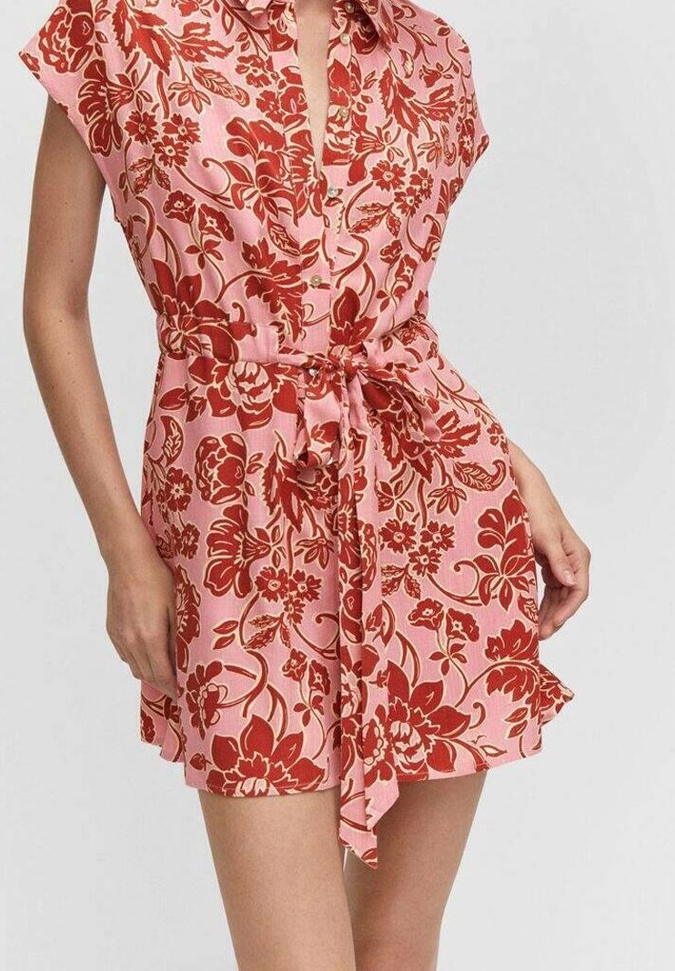 Robe rose à manches courtes avec imprimé floral rouge, dotée d'une fermeture à boutons sur le devant et d'une taille à nouer, fabriquée en tissu léger. Détail volanté au bas.