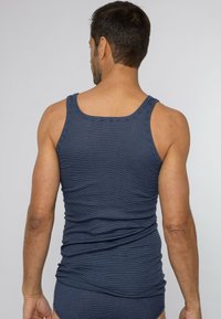 Granatowy top na szerokich ramiączkach w paski, dopasowany fason o gładkiej fakturze, widoczny tył i ramiona.