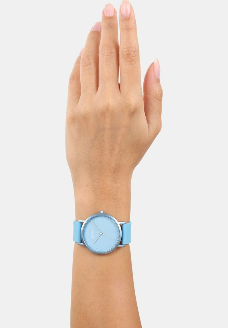 Lichtblauw horloge met een gladde siliconen band en een ronde metalen kast. De wijzerplaat heeft minimale markeringen en zilveren wijzers.
