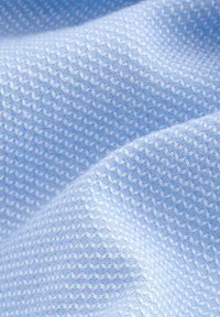 Hellblauer strukturierter Stoff mit einem geometrischen Muster und einem diamantähnlichen Design, gewebt aus feinen Fäden für ein weiches Erscheinungsbild.
