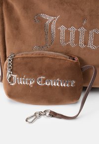 Hnedá semišová kabelka s striebornými kamienkovými detailmi a odnímateľnou malou zipsovou taškou s logom "Juicy Couture" v kovovom písmene.
